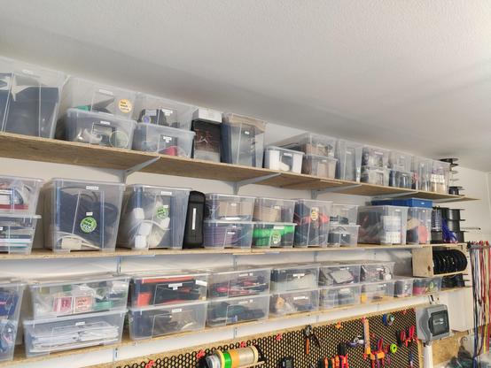 Ein Regalsystem wurde an einer Wand befestigt. 3 Regalbretter gibt es. In diesen stehen Samla Boxen von Ikea. Diese sind durchsichtig, dass der Inhalt sofort erkennbar ist. Zusätzlich noch beschriftet.