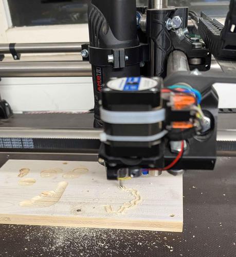 Eine Holzplatte ist an einer CNC Fräse befestigt. 